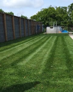 Law mowing residential property with fence lining